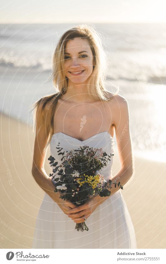 Charmante junge Braut mit Blumen am Strand Frau Blumenstrauß Fröhlichkeit Porträt heiter Menschliches Gesicht Kleid verliebt Liebe elegant Engagement Ausdruck