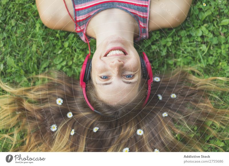 Aufgeregtes Mädchen in Kopfhörern auf Gras Frau expressiv Körperhaltung lügen Park Gesichtsbehandlung Blume Aufregung Model Ausdruck Stil Jugendliche hören