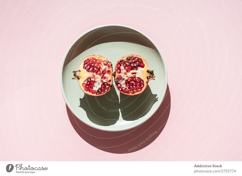 Granatapfelhälften im Sonnenlicht Hälften minimalistisch reif rot Frucht süß Kreativität saftig Abschnitt organisch Teller Schatten mehrfarbig Ordnung Speise