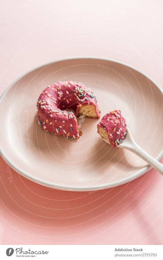 Süßer rosa Doughnut auf Teller Krapfen beißen Studioaufnahme lecker Dessert Kunst süß Spielfigur Süßwaren Feinschmecker Ernährung Kreativität Essen Löffel