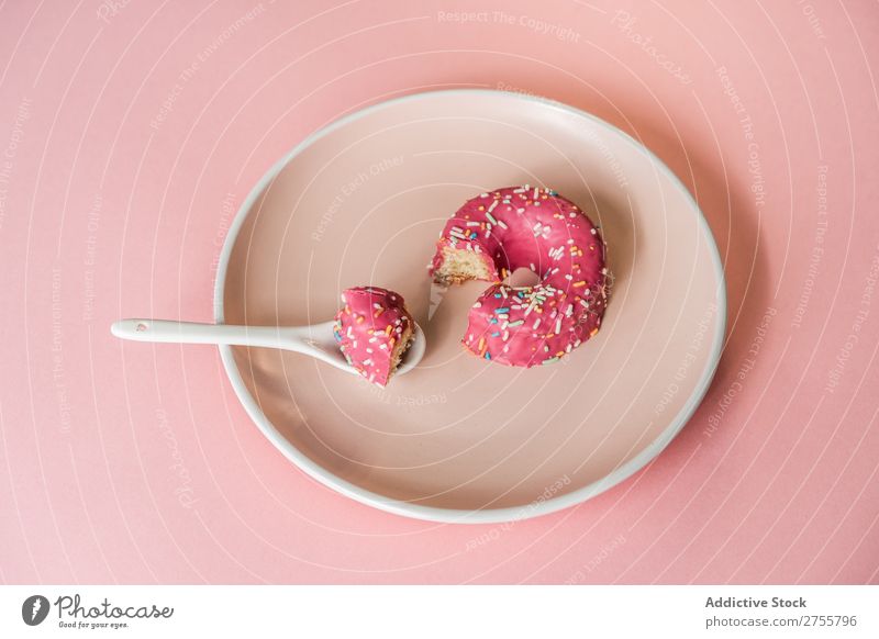 Süßer rosa Doughnut auf Teller Krapfen beißen Studioaufnahme lecker Dessert Kunst süß Spielfigur Süßwaren Feinschmecker Ernährung Kreativität Essen Löffel
