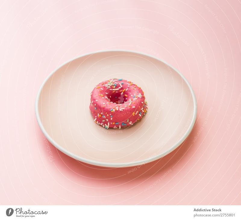 Süßer rosa Doughnut auf Teller Krapfen minimalistisch süß Symmetrie Studioaufnahme Lebensmittel Backwaren Kunst Dessert Bäckerei Essen zubereiten Gastronomie