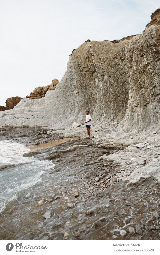 Mann, der auf einem felsigen Strand steht. Tourist Klippe Meer Felsen Ferien & Urlaub & Reisen Tourismus Natur Landschaft Küste Wasser Sonne Freiheit Stein