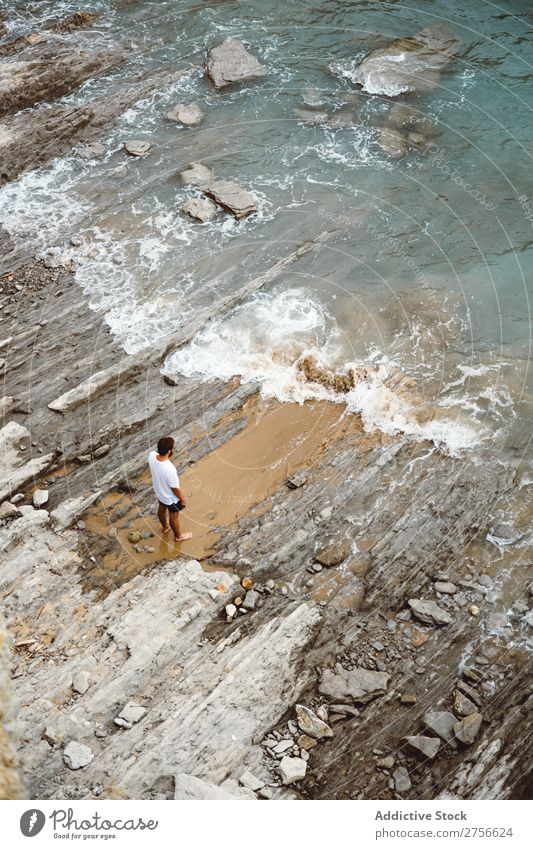 Mann, der auf einem felsigen Strand steht. Tourist Klippe Meer Felsen Ferien & Urlaub & Reisen Tourismus Natur Landschaft Küste Wasser Sonne Freiheit Stein