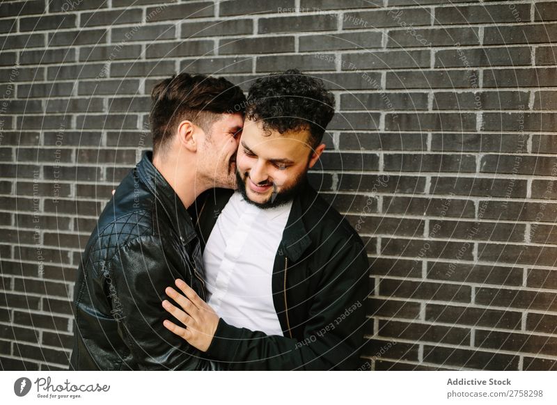 Mann küsst seinen Freund. Paar Homosexualität Küssen Wange Umarmen Lächeln Glück stehen Wand Backstein Körperhaltung paarweise Liebe 2 Zusammensein Lifestyle