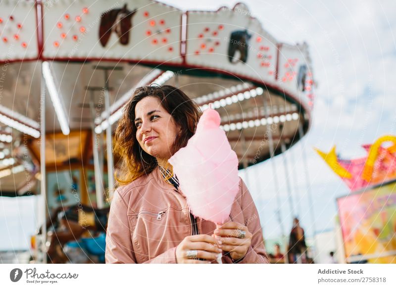 Fröhliche Frau mit Zuckerwatte Park Kinderkarussell Mensch rosa hübsch süß Lebensmittel Fressen Freude Lifestyle Porträt Jugendliche Lächeln Halt Snack