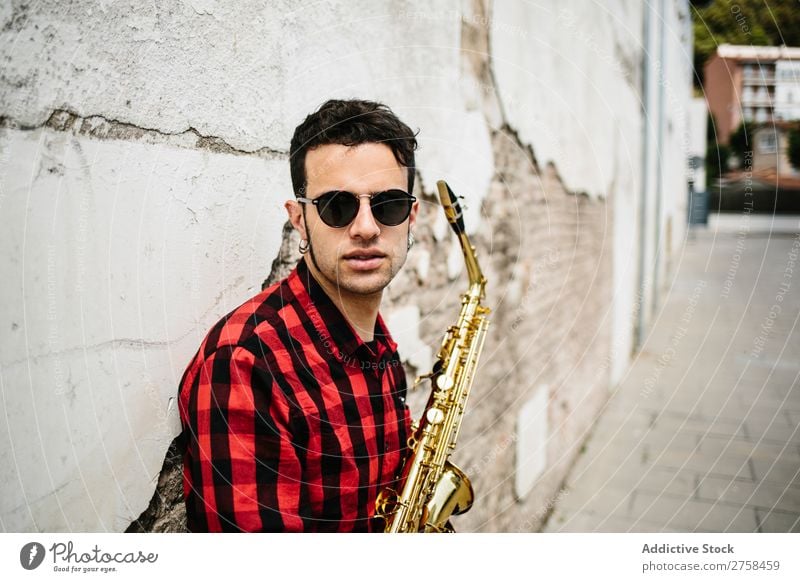 Lächelnder Jazzmann mit Saxophon Musiker Mann Sonnenbrille selbstbewußt Coolness heiter Wand Jugendliche Instrument Musical Leistung Saxophonspieler Mensch