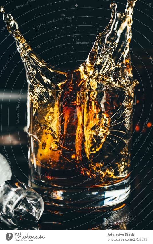 Spritzer von Glas Whiskey Alkohol Getränk Bourbon braun Cocktail kalt Coolness Kristalle Würfel dunkel trinken Tropfen elegant Glaswaren Eis liquide Reichtum