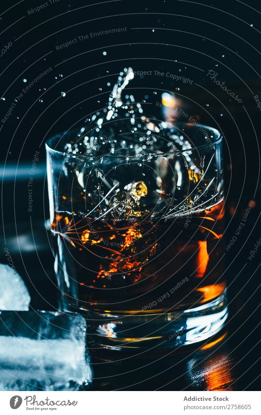 Ein Glas spritzender Whiskey Alkohol Getränk Bourbon braun Cocktail kalt Coolness Kristalle Würfel dunkel trinken Tropfen elegant Vogelperspektive Glaswaren Eis