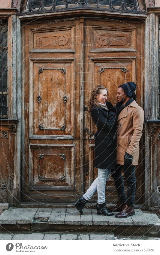 Paar an der Vintage-Tür umarmt multiethnisch Stil Straße warme Kleidung Holz schäbig alt lässig schön Person gemischter Abstammung schwarz Jugendliche
