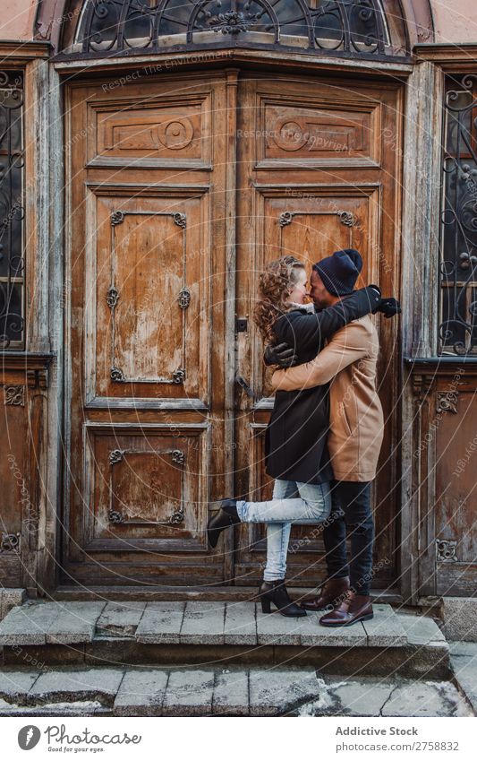Paar an der Vintage-Tür umarmt multiethnisch Stil Straße warme Kleidung Holz schäbig alt lässig schön Person gemischter Abstammung schwarz Jugendliche