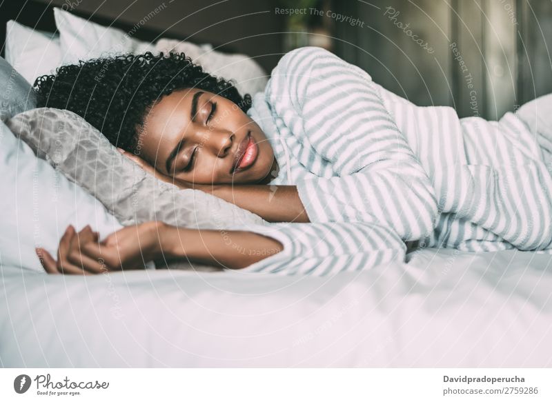 Nahaufnahme einer hübschen schwarzen Frau mit lockigem Haar, die im Bett schläft geschlossene Augen schwarze Frau schlafen Porträt lügen Lächeln Afrikanisch