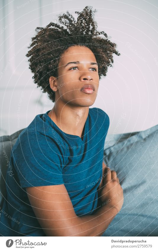 Porträt eines jungen nachdenklichen gemischtrassigen Mannes, der auf dem Sofa sitzt. schwarz Jugendliche Mensch Rennsport Amerikaner Afrikanisch