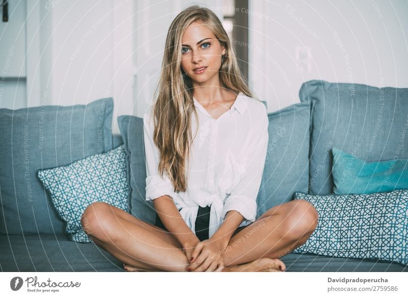Porträt einer jungen nachdenklichen blonden Frau, die auf dem Sofa sitzt. sitzen Liege Raum Lächeln Jugendliche Fürsorge hübsch Nahaufnahme Leben heimwärts