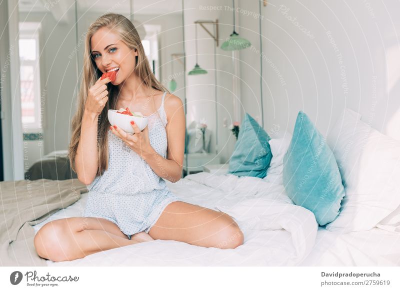 Junge, gesunde, schöne, blonde Frau im Bett, die Früchte isst. Schlafzimmer Porträt Frucht Lebensmittel Fressen Lächeln Jugendliche Mädchen Gesundheit Fürsorge