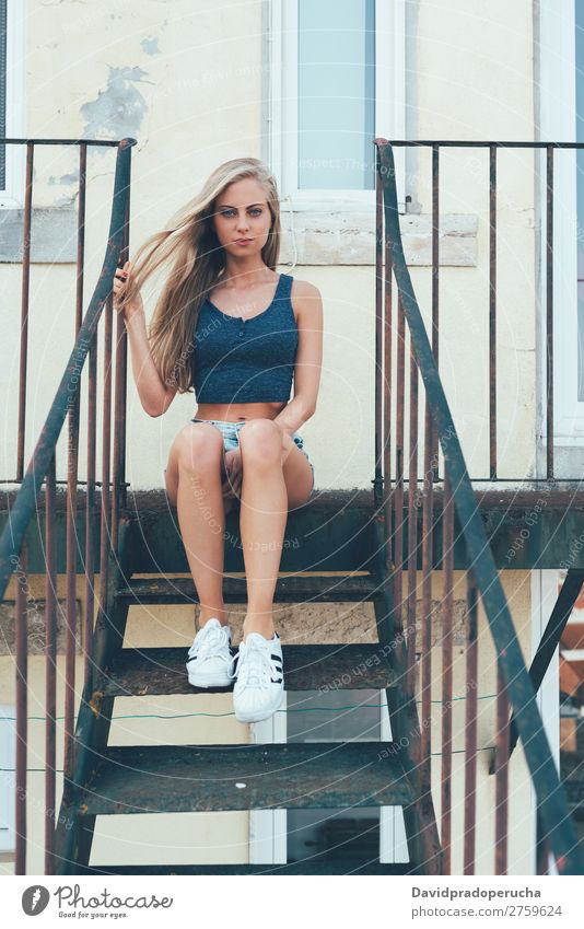 Young fit schöne blonde Frau sitzt auf der Treppe und posiert. Porträt Lächeln Jugendliche Fürsorge hübsch sportlich sitzen blau Auge Gesundheit Erotik