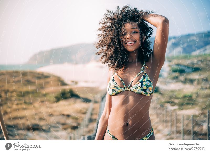 Schöne junge schwarze Frau in einer hölzernen Fußgängerbrücke am Strand. Hintergrundbild Bikini Brücke Küste krause Haare Ausflugsziel Behaarung