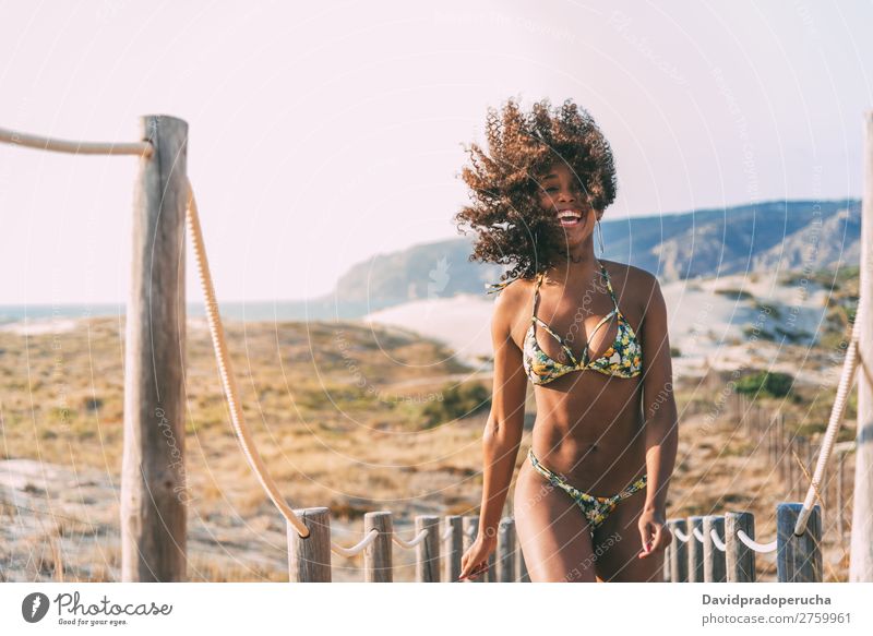 Schöne junge Frau im Bikini in einer Holzsteg am Strand. schwarz Brücke Hintergrundbild Küste krause Haare Ausflugsziel Mädchen niedlich hübsch schön Behaarung
