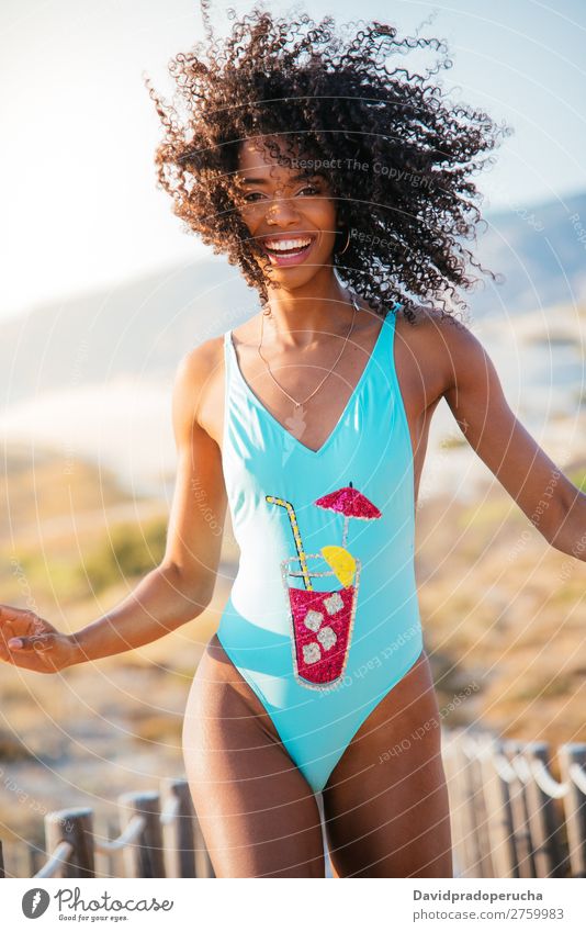 Glückliche schöne junge Frau im Badeanzug in einer Holzsteg am Strand. Bikini Schwimmsport Anzug schwarz Brücke Hintergrundbild Küste krause Haare Ausflugsziel