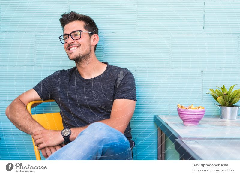 Glücklicher junger Mann, der in einem Restaurant sitzt. Erwachsene Einsamkeit attraktiv schön blau hell Kaukasier Kaffee Café mehrfarbig genießend Lebensmittel