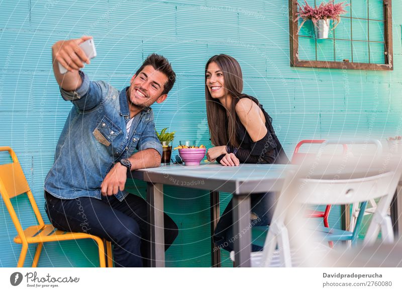 Glückliches junges Paar, das in einem Restaurant sitzt und mit einem Smartphone ein Selfie nimmt. Erwachsene attraktiv Hintergrundbild schön blau Kaukasier