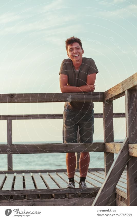 Lächelnder, glücklicher junger Mann, der auf einem Pier über dem Meer steht. Lifestyle Freude Glück Freizeit & Hobby Ferien & Urlaub & Reisen Sommer Mensch