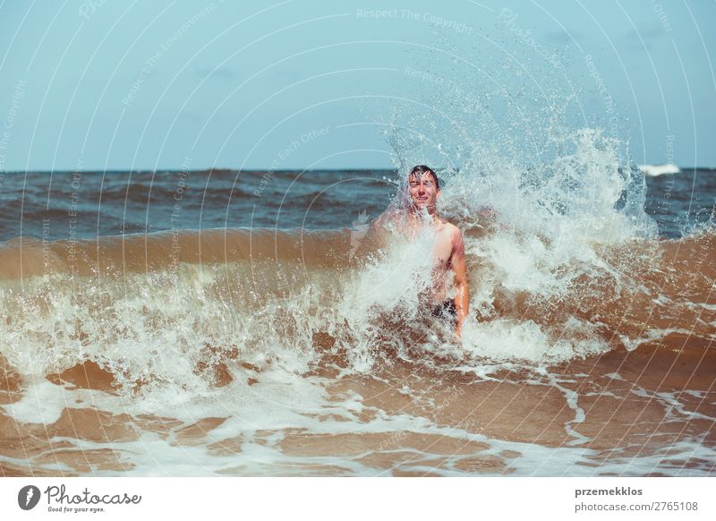 Junger Mann genießt die hohen Wellen im Meer während eines Sommerurlaubs. Verbringen Sie einen Sommerurlaub am Meer Lifestyle Freude Glück Erholung