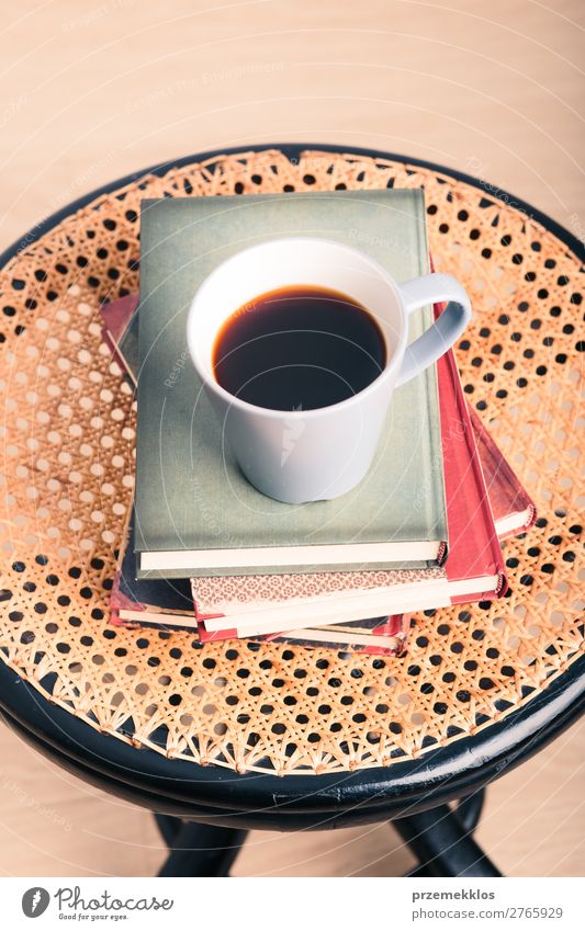 Ein paar Bücher mit einer Tasse Kaffee auf dem Stuhl Becher Lifestyle Erholung Freizeit & Hobby lesen Tisch Buch genießen Geborgenheit bequem gemütlich trinken