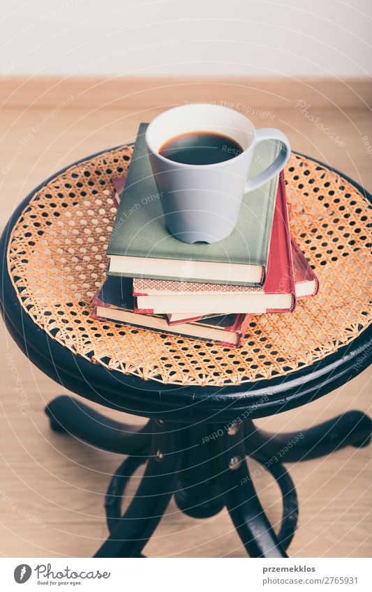 Ein paar Bücher mit einer Tasse Kaffee auf dem Stuhl Becher Lifestyle Erholung Freizeit & Hobby lesen Tisch Buch genießen Geborgenheit bequem gemütlich trinken