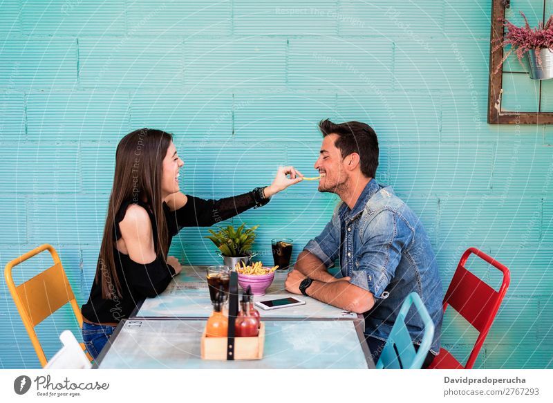 Glückliches junges Paar, das in einem Restaurant sitzt. Erwachsene attraktiv schön Kaukasier Kaffee Cola Essen genießend Frau Lebensmittel Freundschaft Fries