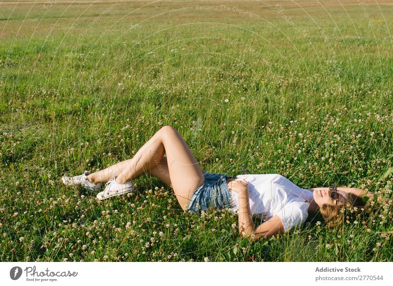 Selbstbewusstes Mädchen, das auf der grünen Wiese posiert. Frau Feld lügen heiter Körperhaltung Fröhlichkeit lässig Freiheit Natur Sommer Landschaft romantisch