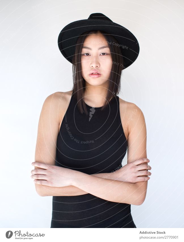 Junge asiatische Frau mit verschränkten Armen Stil modisch Hut schön Mode Beautyfotografie Jugendliche Model Porträt attraktiv elegant Glamour