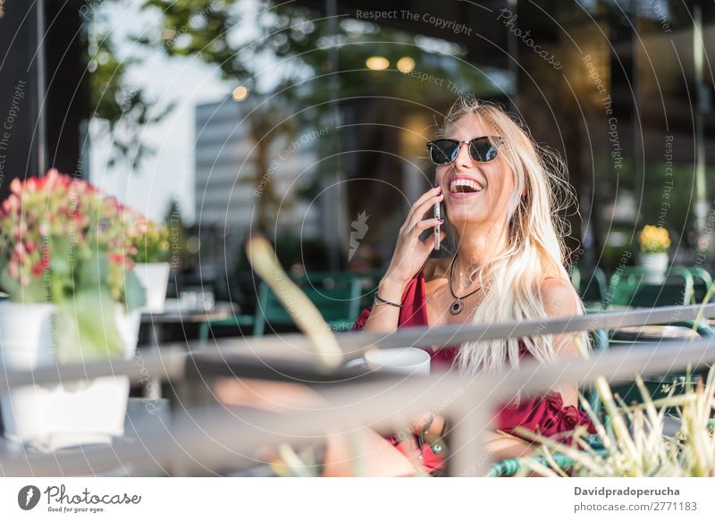 Glückliche blonde schöne Frau mit einem Handy, die eine Tasse Kaffee auf der Terrasse trinkt. Lächeln PDA Sonnenbrille Restaurant Kantine Schüler vereinzelt