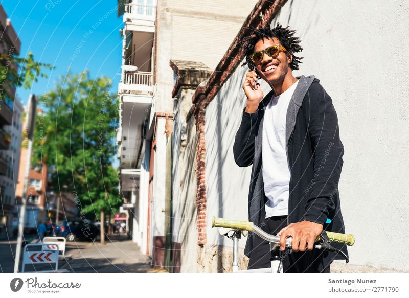 Afrojunger Mann mit Handy und festem Fahrrad. Jugendliche Afrikanisch schwarz Mulatte Afro-Look Mobile Fixie Telefon Lifestyle stehen Fahrradfahren benutzend