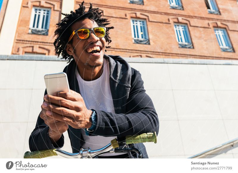 Afrojunger Mann mit Handy und festem Fahrrad. Jugendliche Afrikanisch schwarz Mulatte Afro-Look Mobile Fixie Telefon Lifestyle stehen Fahrradfahren benutzend