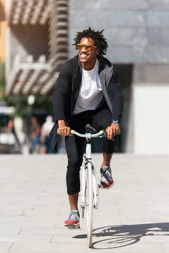 Gutaussehender Afro-Mann auf einem Fahrrad. Jugendliche Afro-Look schwarz Mulatte Afrikanisch Fixie Schickimicki Lifestyle Fahrradfahren Großstadt Stadt Mensch