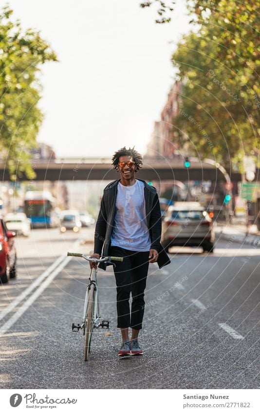 Ein gutaussehender Afro-Mann, der mit seinem Fahrrad unterwegs ist. Jugendliche Afro-Look schwarz Mulatte Afrikanisch Fixie Schickimicki Lifestyle Fahrradfahren