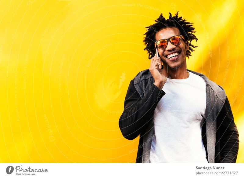 Porträt eines gutaussehenden Afro-Mannes mit seinem Handy. Jugendliche Afrikanisch schwarz Mulatte Afro-Look Mobile Telefon Lifestyle stehen benutzend