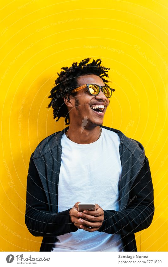 Porträt eines gutaussehenden Afro-Mannes mit seinem Handy. Jugendliche Afrikanisch schwarz Mulatte Afro-Look Mobile Telefon Lifestyle stehen benutzend
