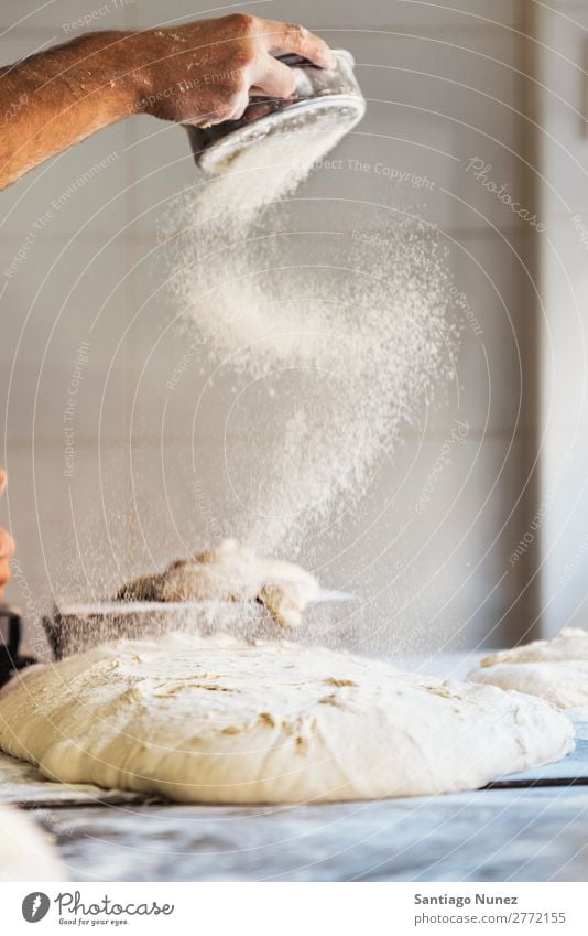 Bäckermeister, der mit der Hand Mehl zu Teig streicht. Brot Bäckerei Teigwaren Lebensmittel kochen & garen machen Kneten Aufstrich Tisch Beruf Backwaren Fabrik