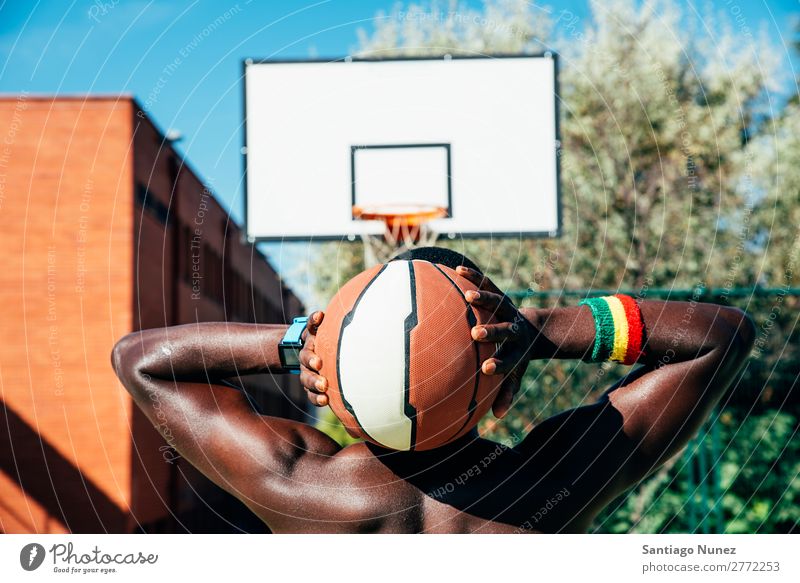 Männlicher Basketballspieler, der einen Ball hält. Aktion Afroamerikaner Rücken Rückansicht Korb schwarz Großstadt Stadtleben Gerichtsgebäude Tag üben Spielen