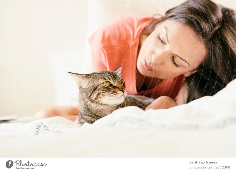 Glückliche Frau, die ihre Katze im Schlafzimmer küsst. Mädchen Umarmen Tier Haustier Küssen Katzenbaby niedlich schön Mensch Liebe heimwärts Gesicht Mode weiß