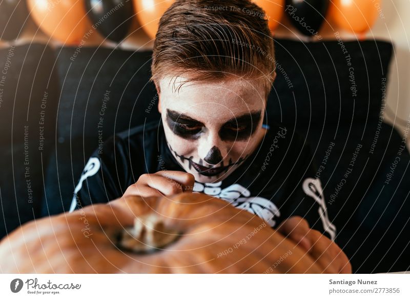 Ein fröhlicher Junge verkleidet, der zu Hause einen Kürbis schmückt. Halloween Kind malen Skelett Freude Familie & Verwandtschaft Hermano Porträt Angst