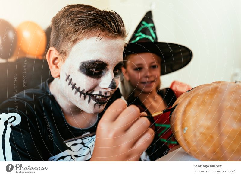 Glückliche Kinder verkleideten sich und schmückten zu Hause einen Kürbis. Halloween Mädchen Junge malen Skelett Hexe Freude Familie & Verwandtschaft Schwester