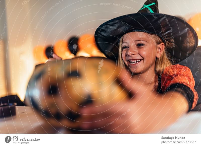 Schönes Mädchen verkleidet von einer Hexe, die zu Hause einen Kürbis schmückt. Halloween Kind malen Freude Familie & Verwandtschaft Schwester Porträt Angst