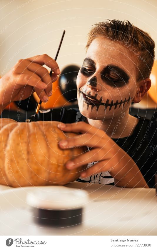 Glücklicher Junge, der zu Hause einen Kürbis schmückt. Halloween Kind malen Skelett Freude verkleidet Familie & Verwandtschaft Hermano Porträt Angst