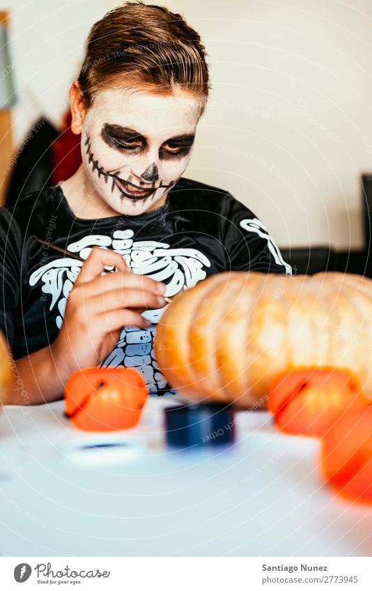Ein fröhlicher Junge verkleidet, der zu Hause einen Kürbis schmückt. Halloween Konzept. Kind malen Skelett Freude Familie & Verwandtschaft Hermano Porträt Angst