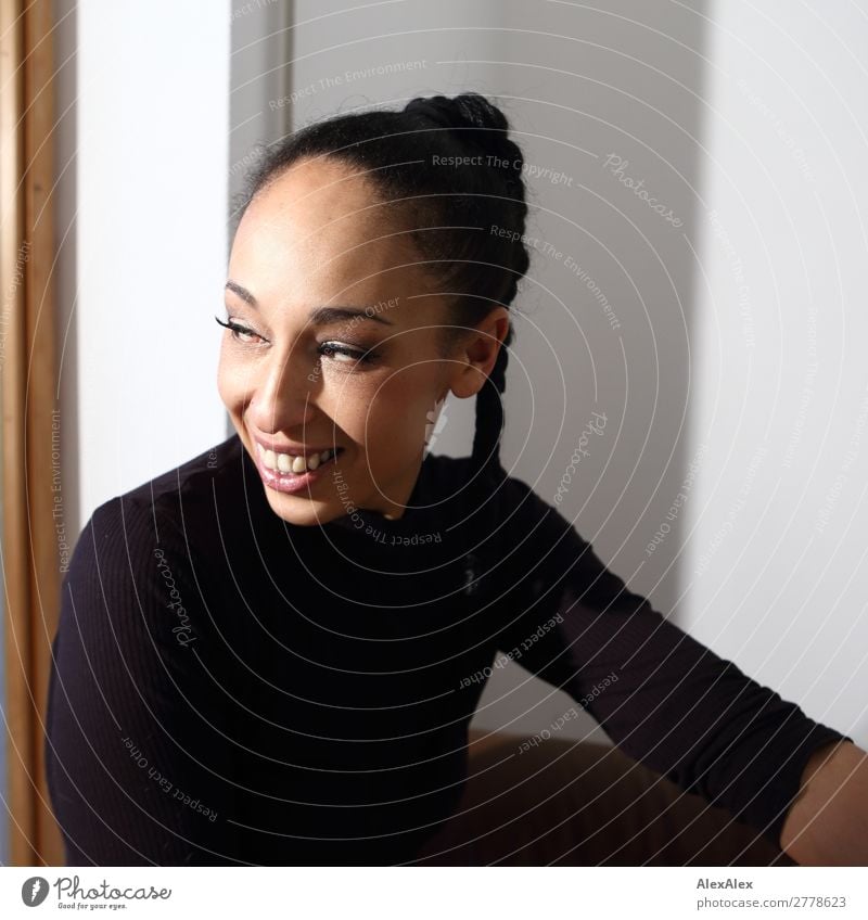 Portrait einer Frau mit Zopf Freude schön Zufriedenheit Junge Frau Jugendliche 18-30 Jahre Erwachsene 30-45 Jahre T-Shirt schwarzhaarig Locken Lächeln sitzen