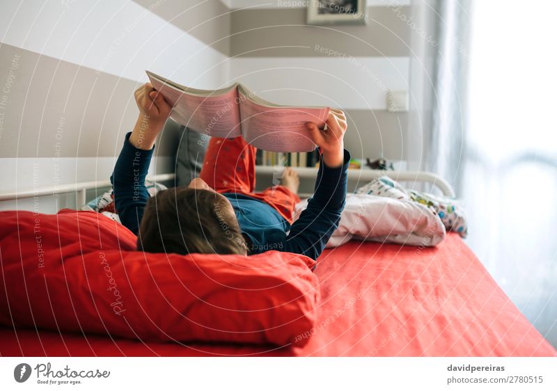 Unbekannter Junge, der auf dem Bett liegend ein Buch liest Lifestyle Freude Windstille Freizeit & Hobby lesen Schlafzimmer Kind Mensch Mann Erwachsene Kultur