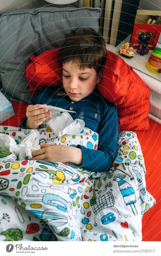 Kaltes Kind schaut auf das Thermometer. Lifestyle Krankheit Erholung Schlafzimmer Mensch Junge Mann Erwachsene Kindheit Buch Fluggerät Spielzeug authentisch